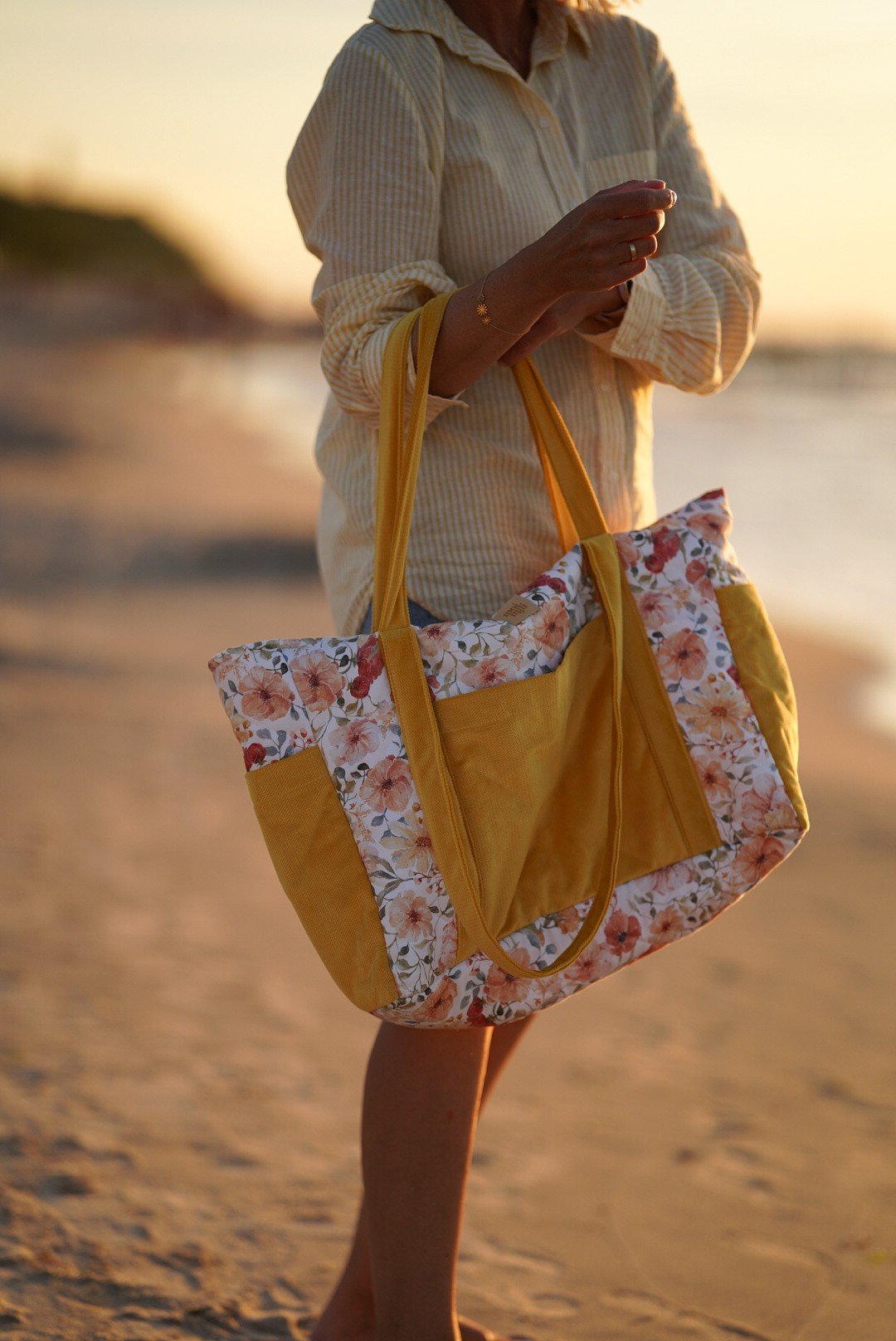 3. Woman carrying yellow and floral weekender bag on beach during sunset
