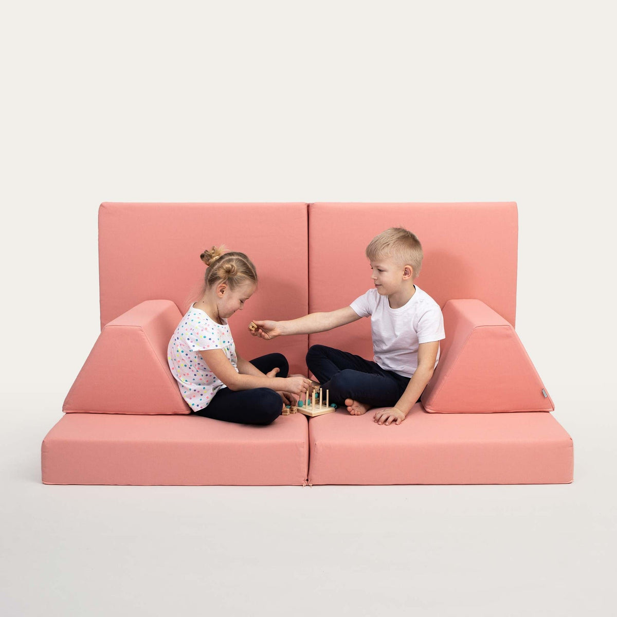 1. Two children playing on Monboxy salmon pink activity play mattress set with trapezoidal pillows in a studio setting