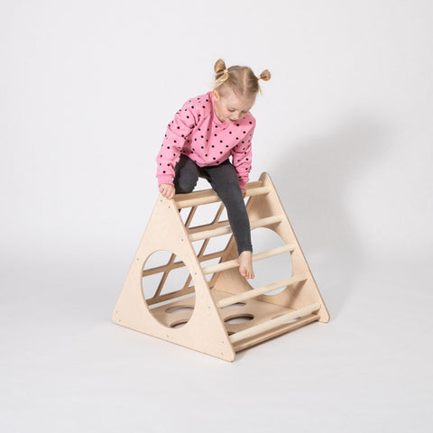1. Young girl in pink polka dot sweater climbing Montessori 3-angle climber in studio setting