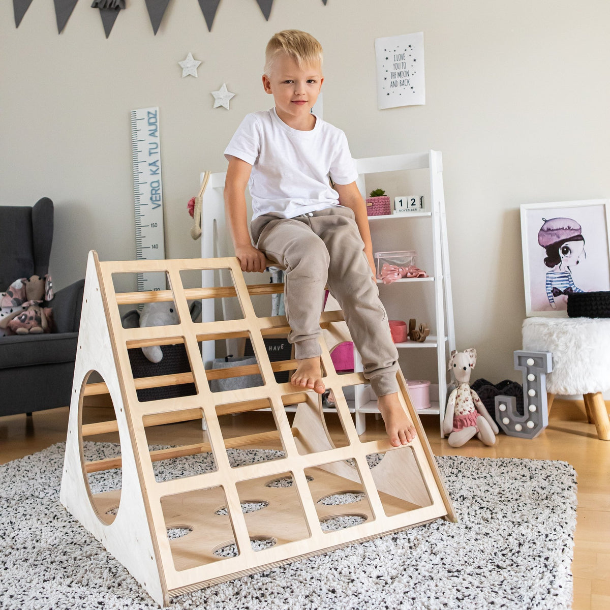 1. Young boy in white shirt sitting on Montessori 3-angle climber in a playroom setting