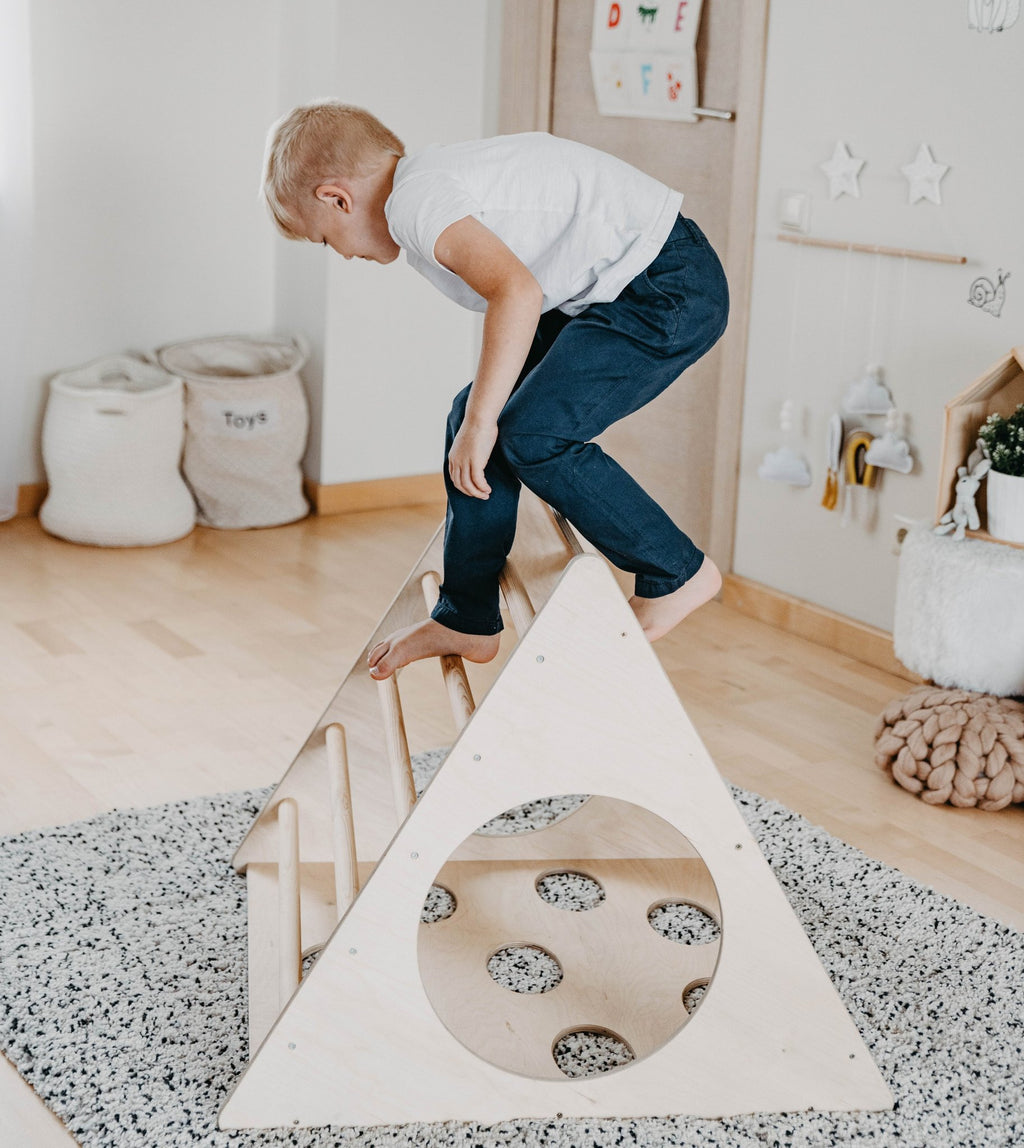 1. Young boy in white shirt climbing Montessori 3-angle climber in a playroom setting