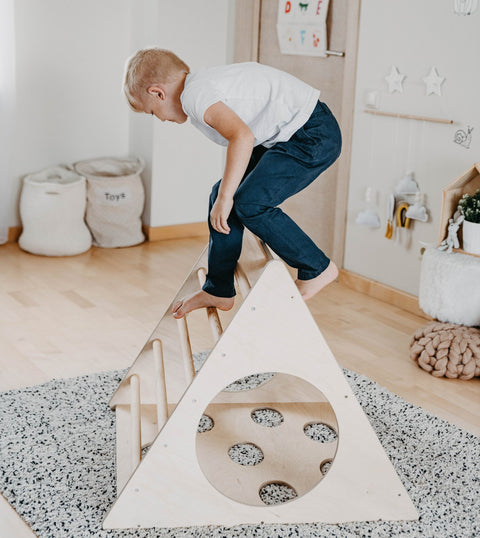 1. Young boy in white shirt climbing Montessori 3-angle climber in a playroom setting
