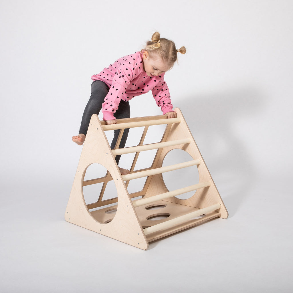 1. Young girl in pink polka dot sweater climbing down Montessori 3-angle climber in studio setting
