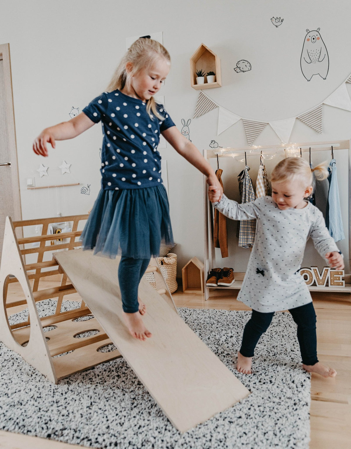 3. Two young girls playing on Montessori wooden climber with ramp in decorated playroom
