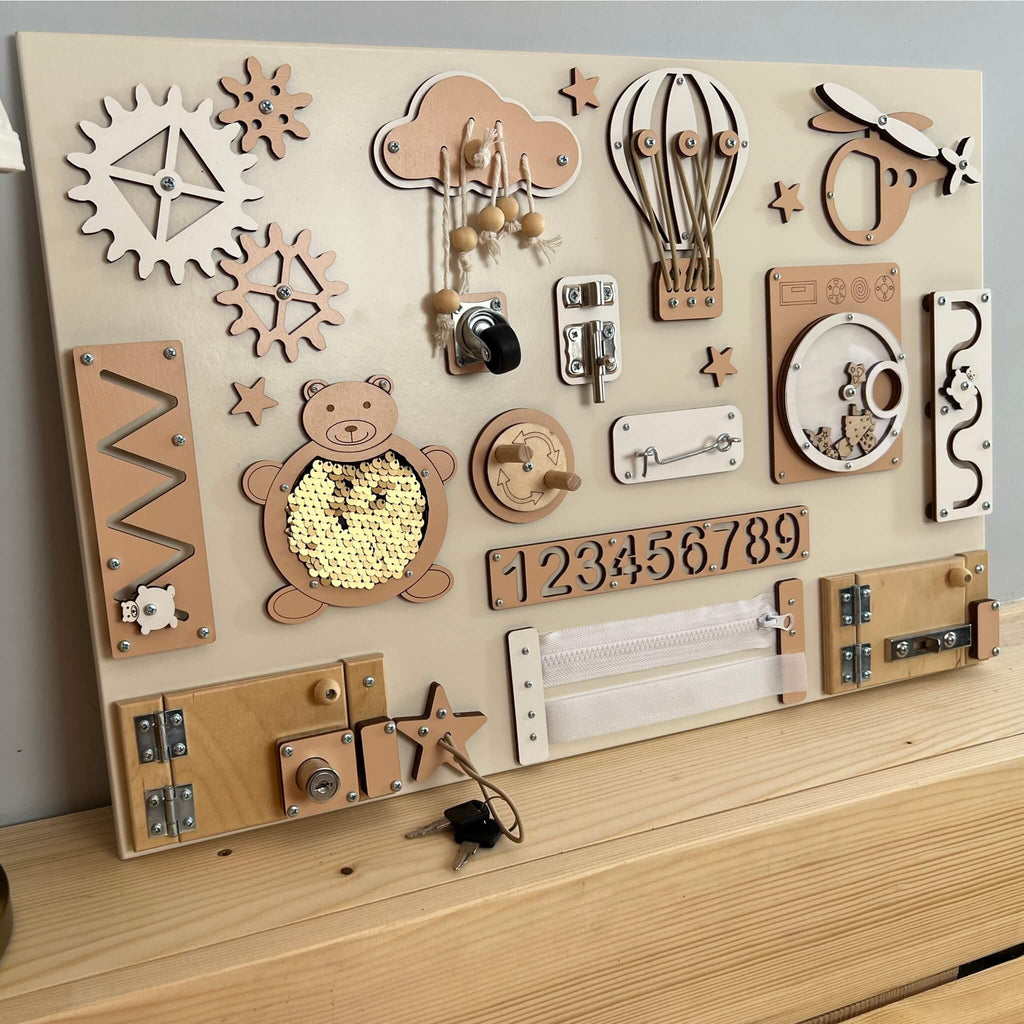 2. Montessori busy board with beige and brown elements including locks, gears, and numbers on a wooden surface