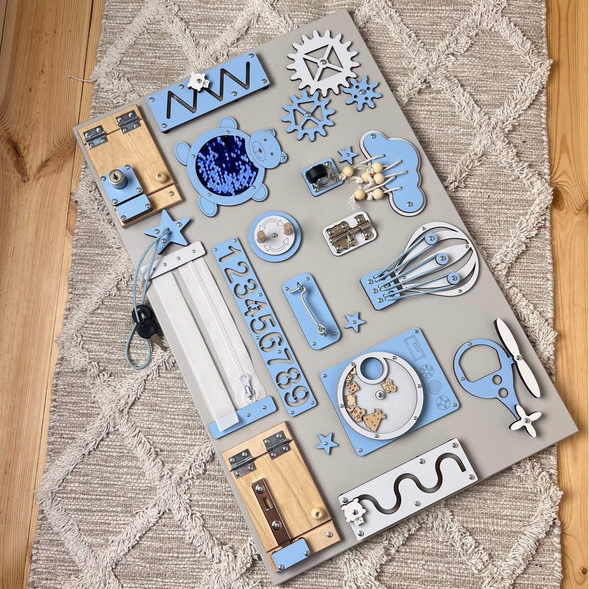 4. Flat lay of blue Montessori busy board with locks, gears, and numbers on a wooden floor