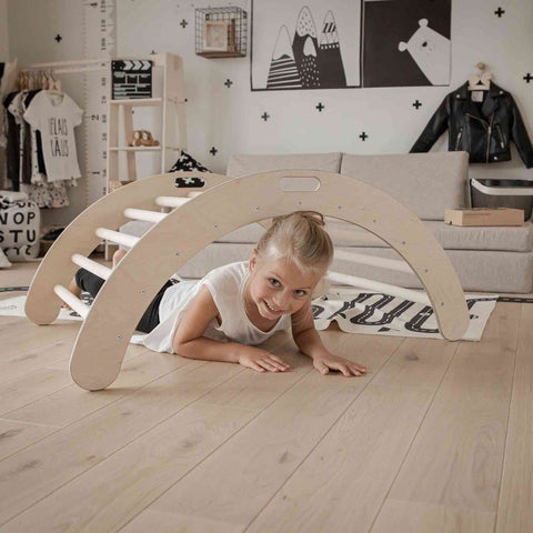 3. Child crawling under a wooden Montessori climbing arch in a modern playroom with monochrome decor