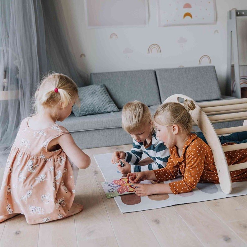 3. Three children playing around wooden Montessori climbing arch in cozy playroom