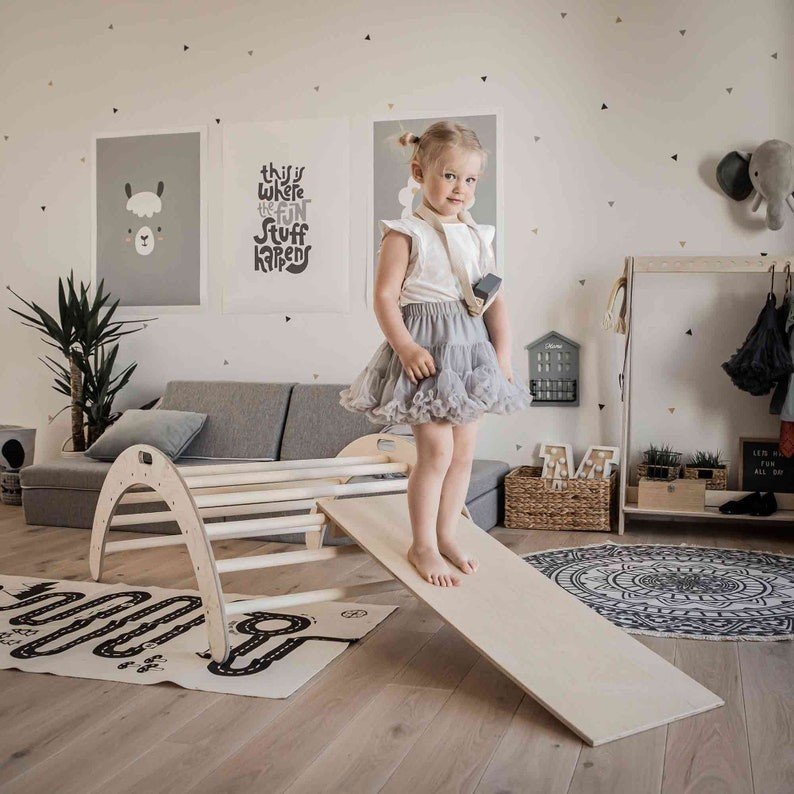6. Girl in grey tutu standing on Montessori climbing arch with ramp in stylish playroom