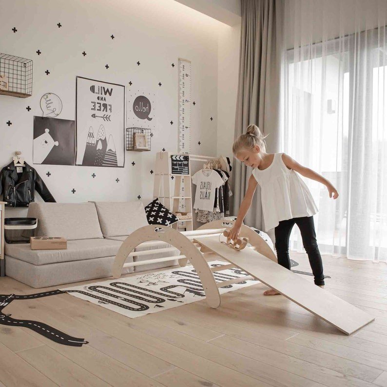 4. Girl in white top playing with toy car on Montessori climbing arch with ramp in modern playroom