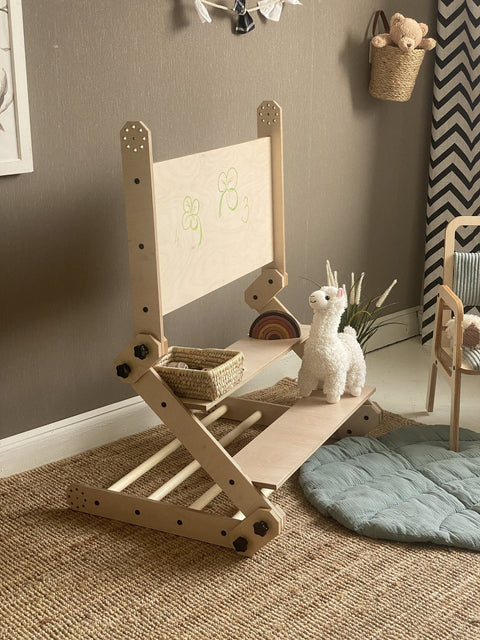 1. Montessori climbing set in natural wood finish with a whiteboard back, placed in a cozy playroom setting with a plush llama toy on a woven rug.