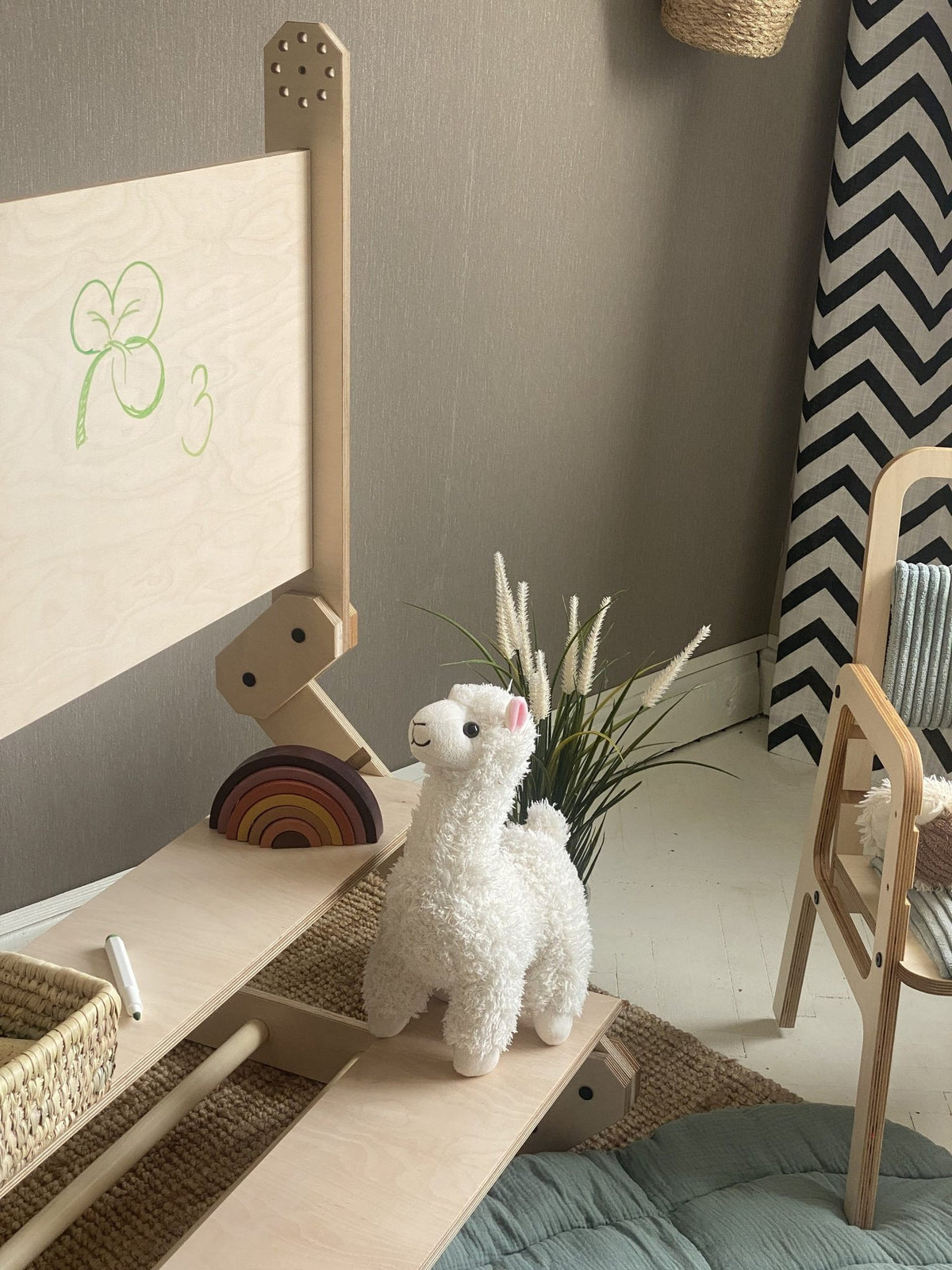 11. Montessori climbing set with a plush llama and bear, in a playroom with a blue cushion and decorative wall art.