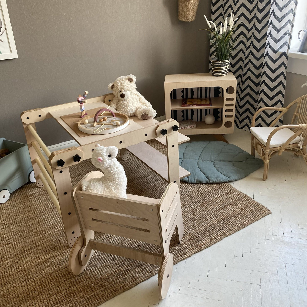 14. Montessori climbing set with plush toys and a blue cushion, in a playroom with decorative wall art and a woven rug.