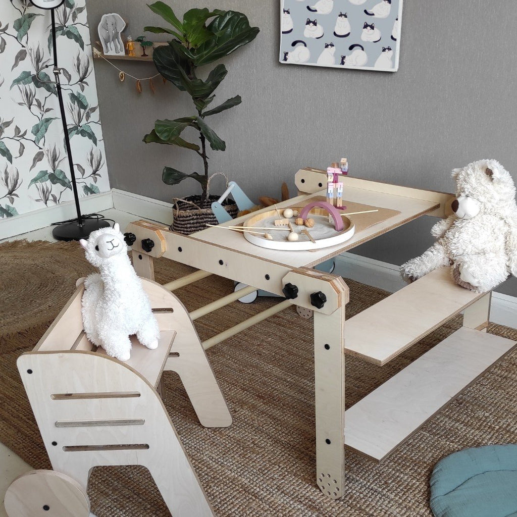 10. Montessori climbing set with a table and plush toys, in a playroom with a plant and decorative wall art.