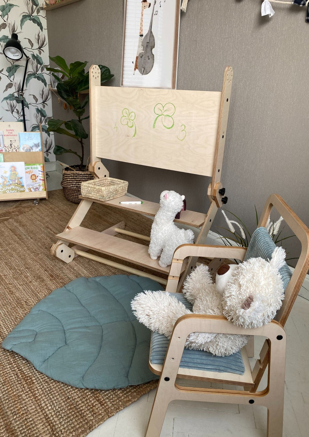 4. Montessori climbing set with a whiteboard and plush toys, set in a playroom with a blue cushion and decorative wall art.