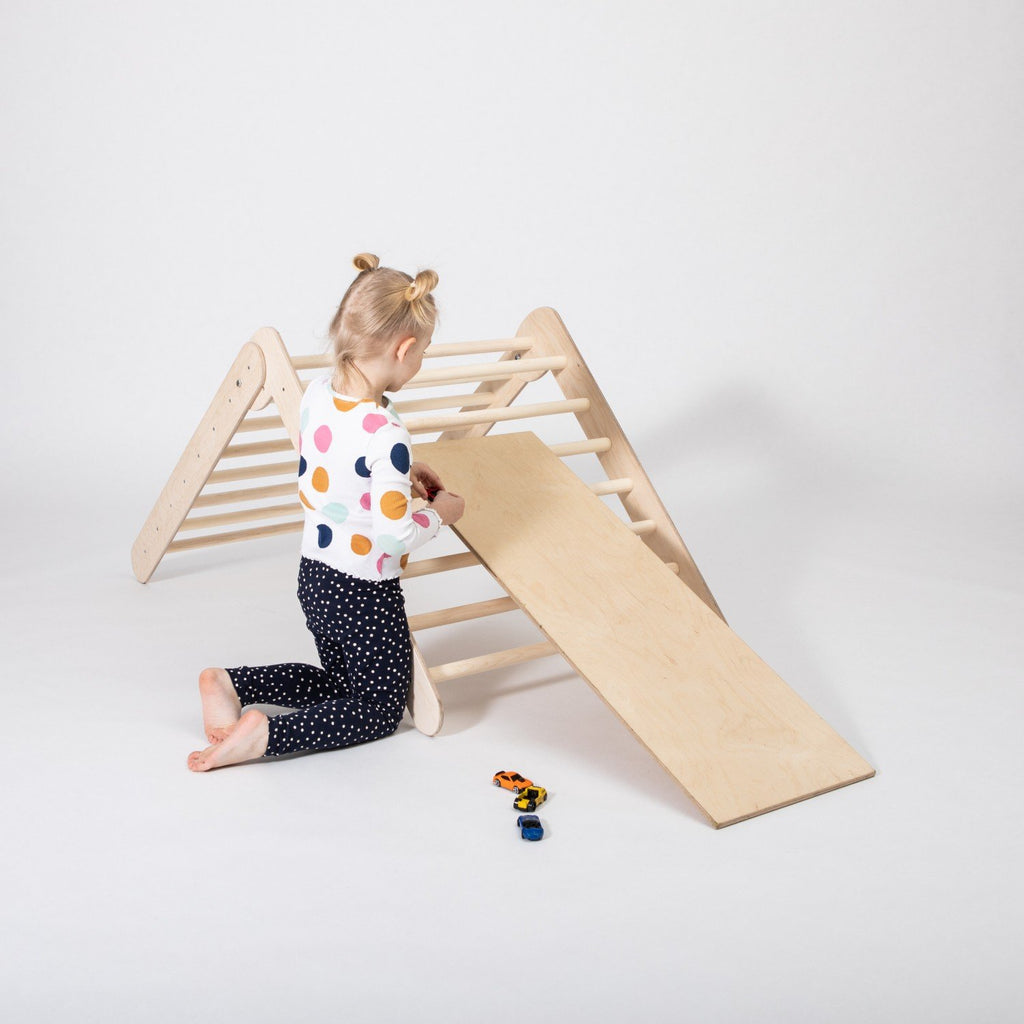 3. Close-up of toddler interacting with Montessori climbing triangle and ramp, highlighting play potential