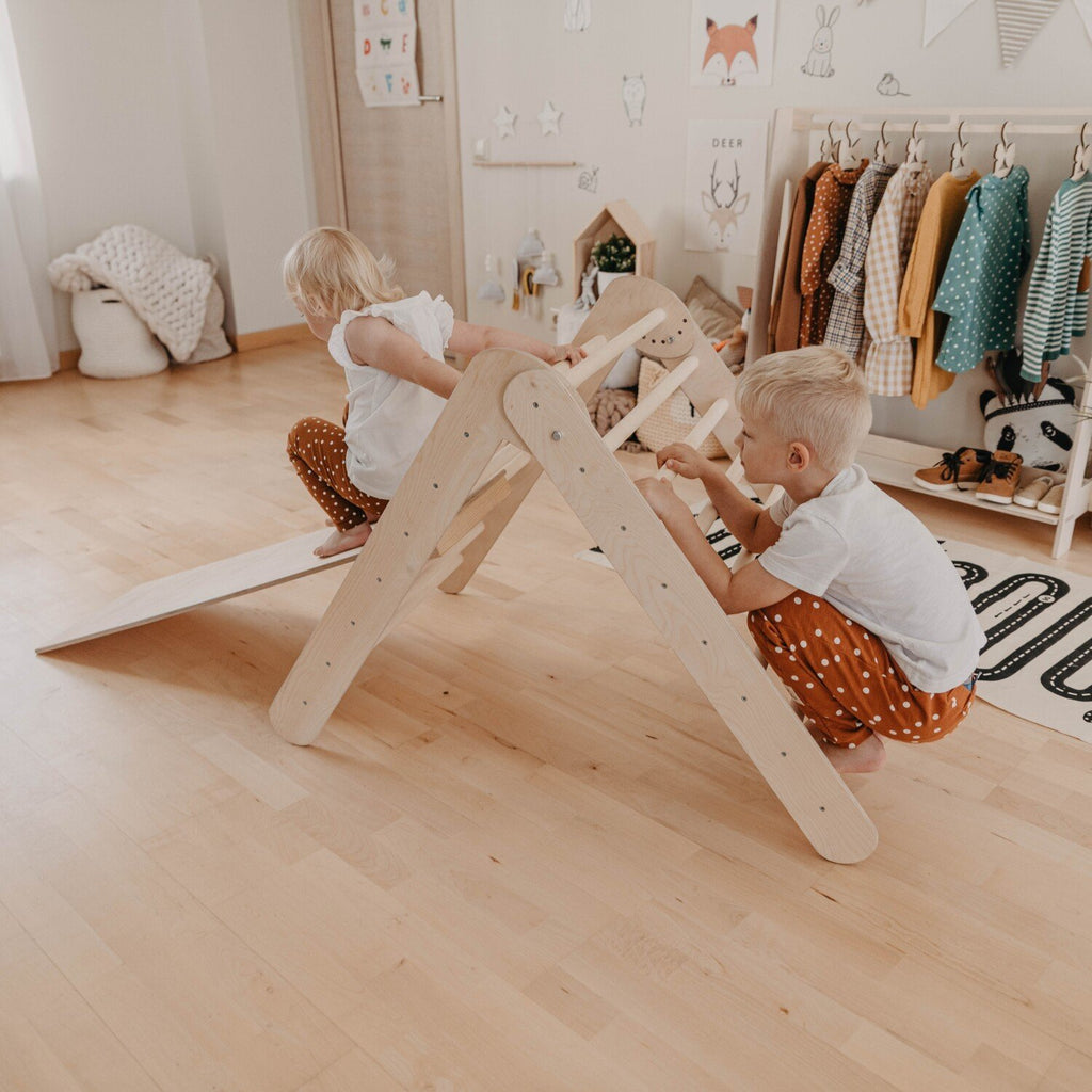 1. Two children climbing on Montessori triangle with ramp in a playroom, highlighting social play