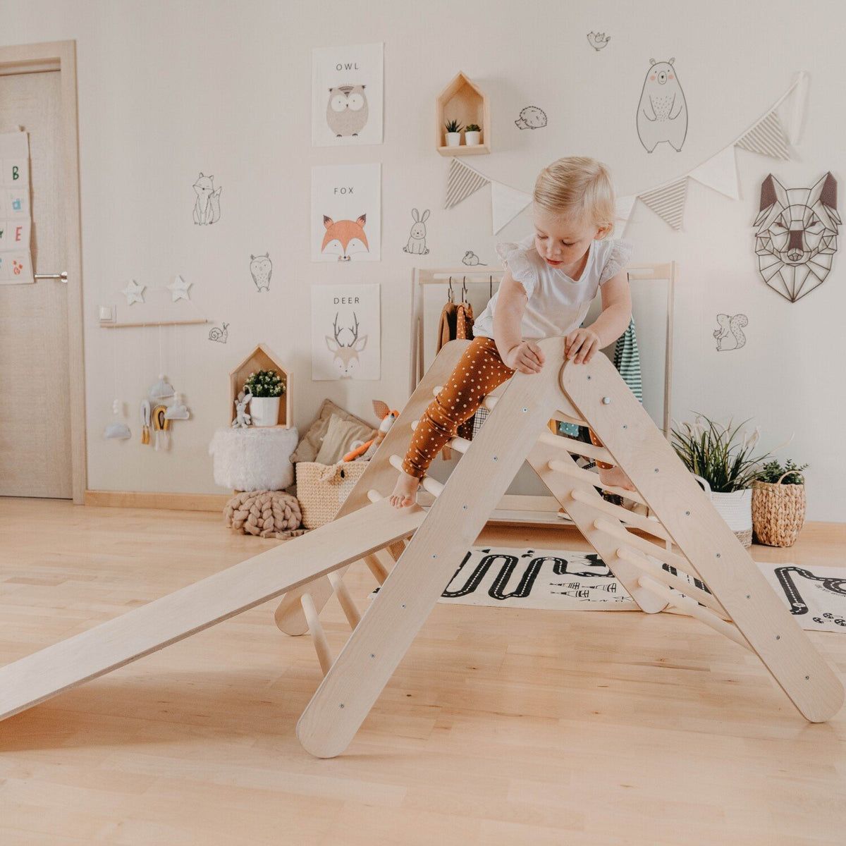 1. Child playing on Montessori climbing triangle with ramp in a decorated playroom, emphasizing exploration