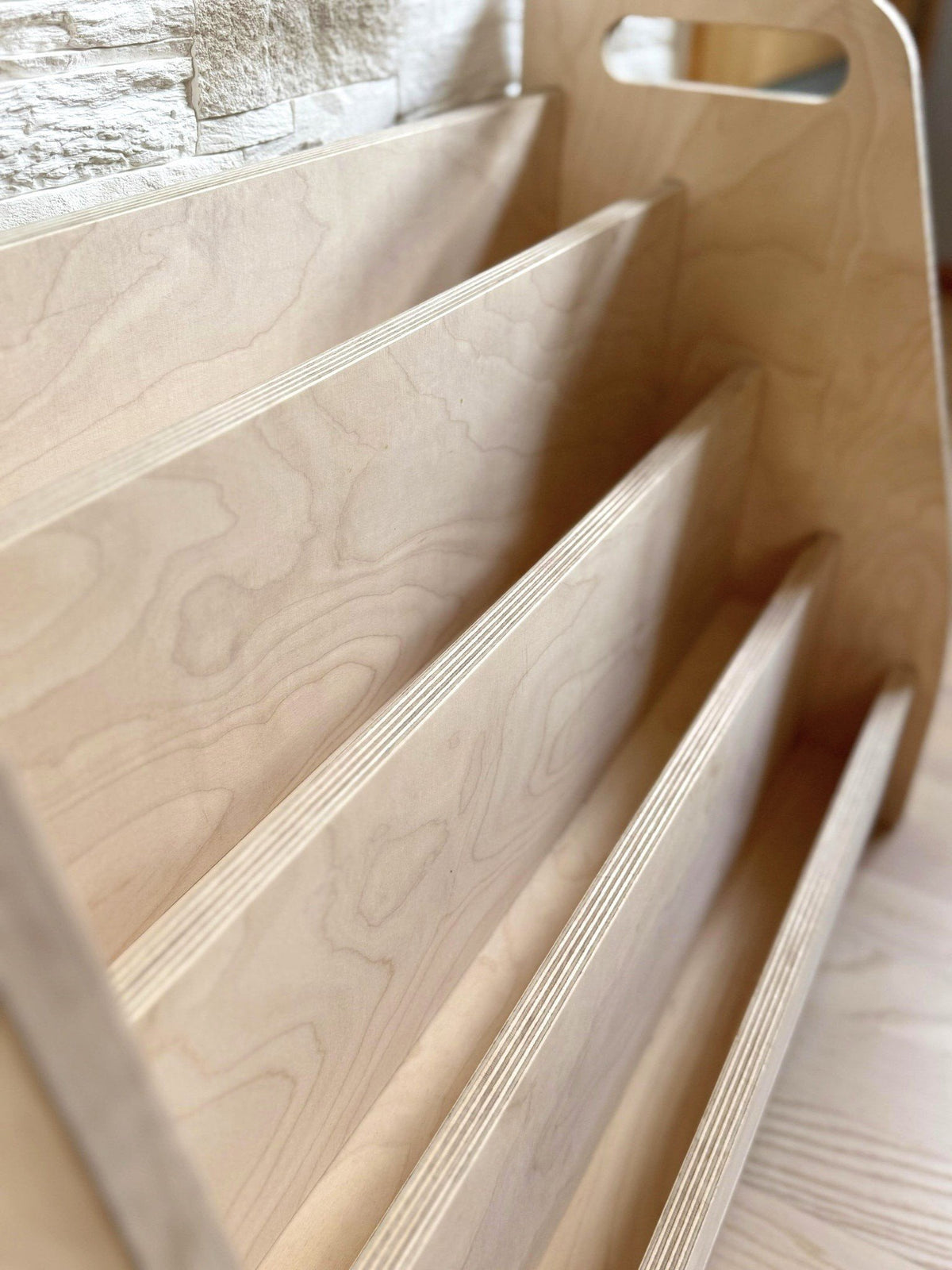 3. Close-up of the birch plywood texture and construction details of the Montessori book display's front-facing tiers.