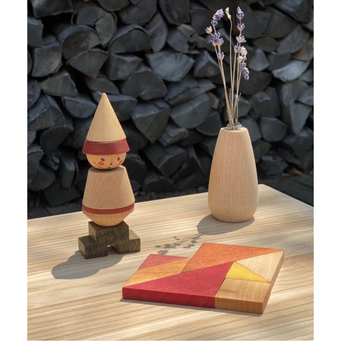 4. Wooden Story tangram set on a wooden table with a wooden figure and vase in an outdoor setting