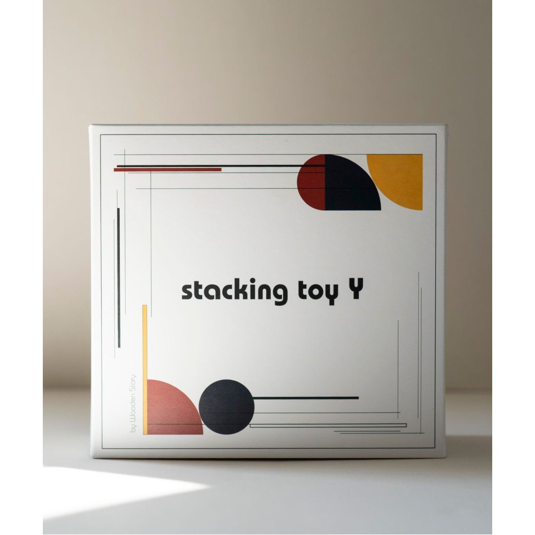 4. Packaging of Wooden Story's stacking toy Y with geometric design and text on a light background
