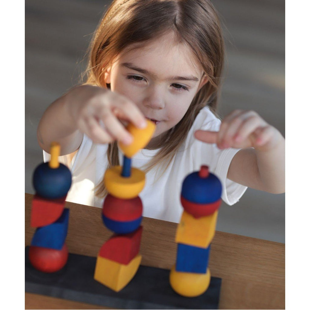 1. Young girl playing with colorful wooden stacking toy on a table, natural light