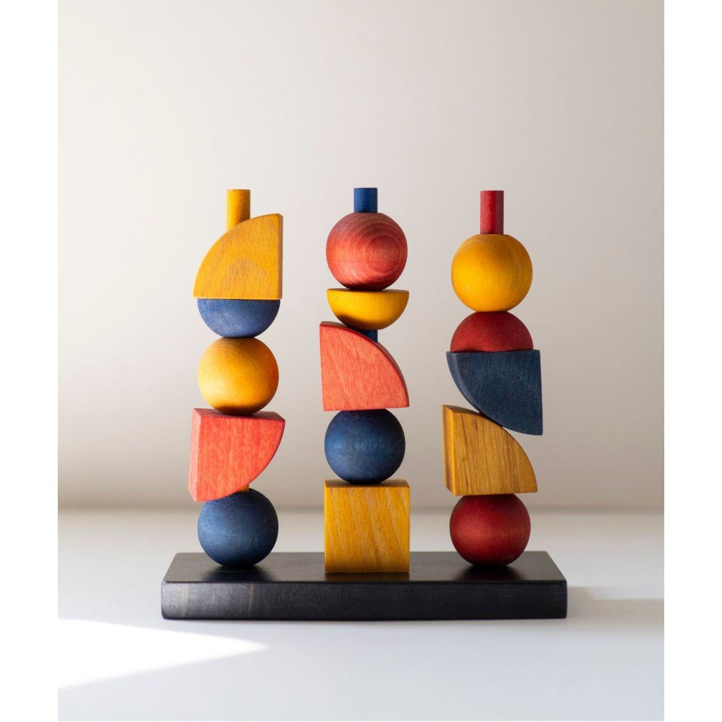 2. Bauhaus-inspired wooden stacking toy with colorful geometric shapes on a black base, studio setting