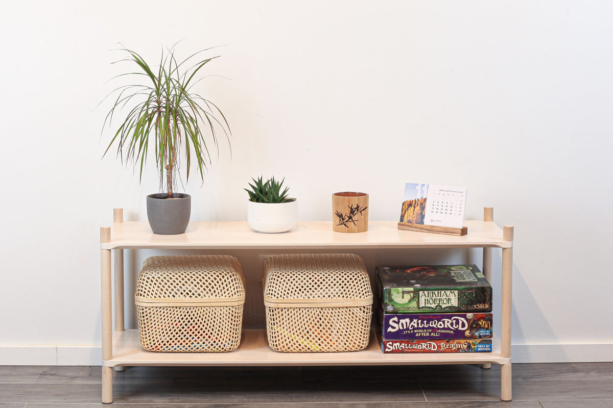 1. Montessori-inspired wooden shelving unit with two shelves, featuring potted plants and woven baskets, in a modern living room setting