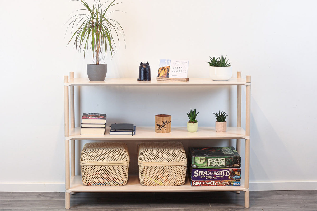 1. Montessori-inspired wooden shelving unit with three shelves, decorated with plants, books, and baskets, in a home setting
