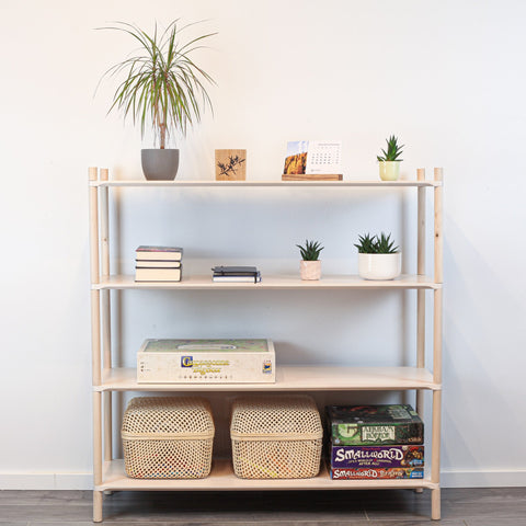 1. Montessori-inspired wooden shelving unit with four shelves, styled with books, plants, and baskets, against a white wall