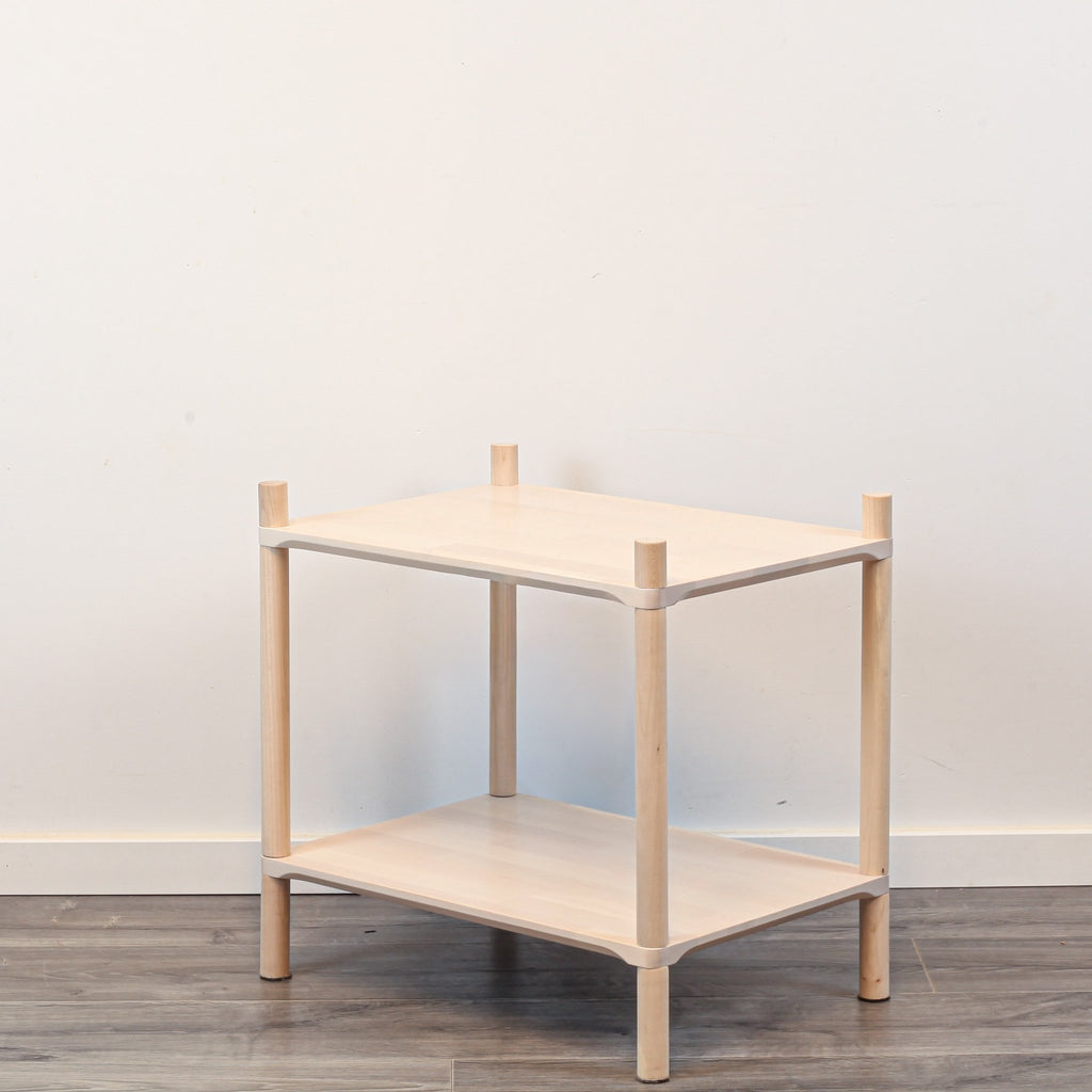 3. Side view of Montessori-inspired wooden shelving unit with two shelves, showcasing rounded corners and natural birch wood finish, against a white wall and wooden floor.