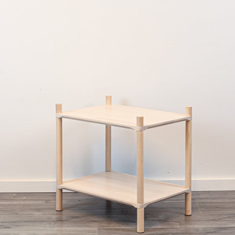 3. Side view of Montessori-inspired wooden shelving unit with two shelves, showcasing rounded corners and natural birch wood finish, against a white wall and wooden floor.