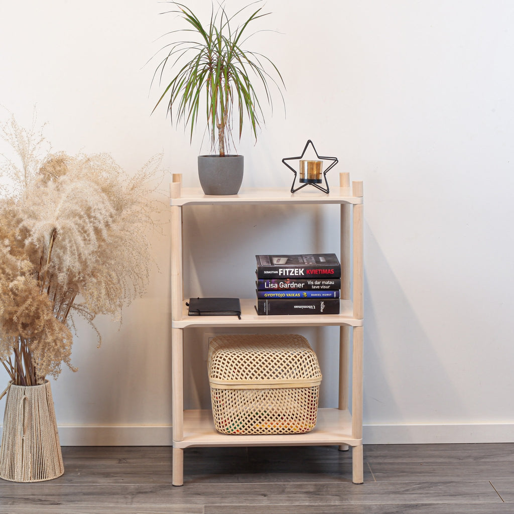 1. Montessori-inspired wooden shelving unit with three shelves, featuring a potted plant, books, and a decorative star on top, set against a white wall with pampas grass on the side