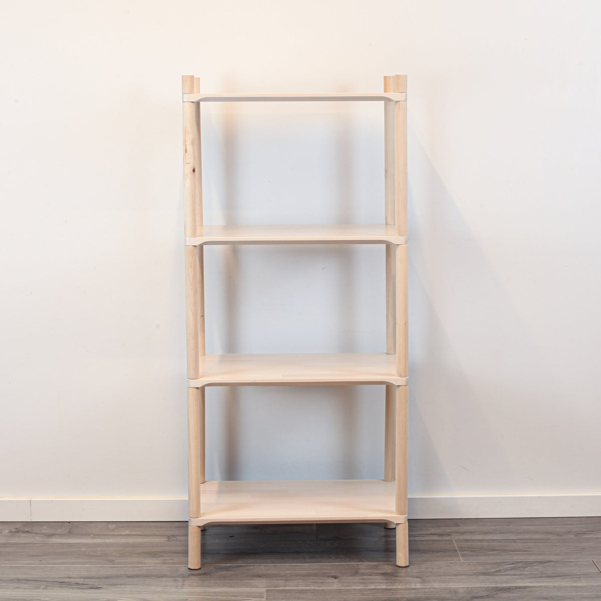 3. Front view of Montessori-inspired wooden shelving unit with four shelves, crafted from natural birch wood, displayed against a white wall