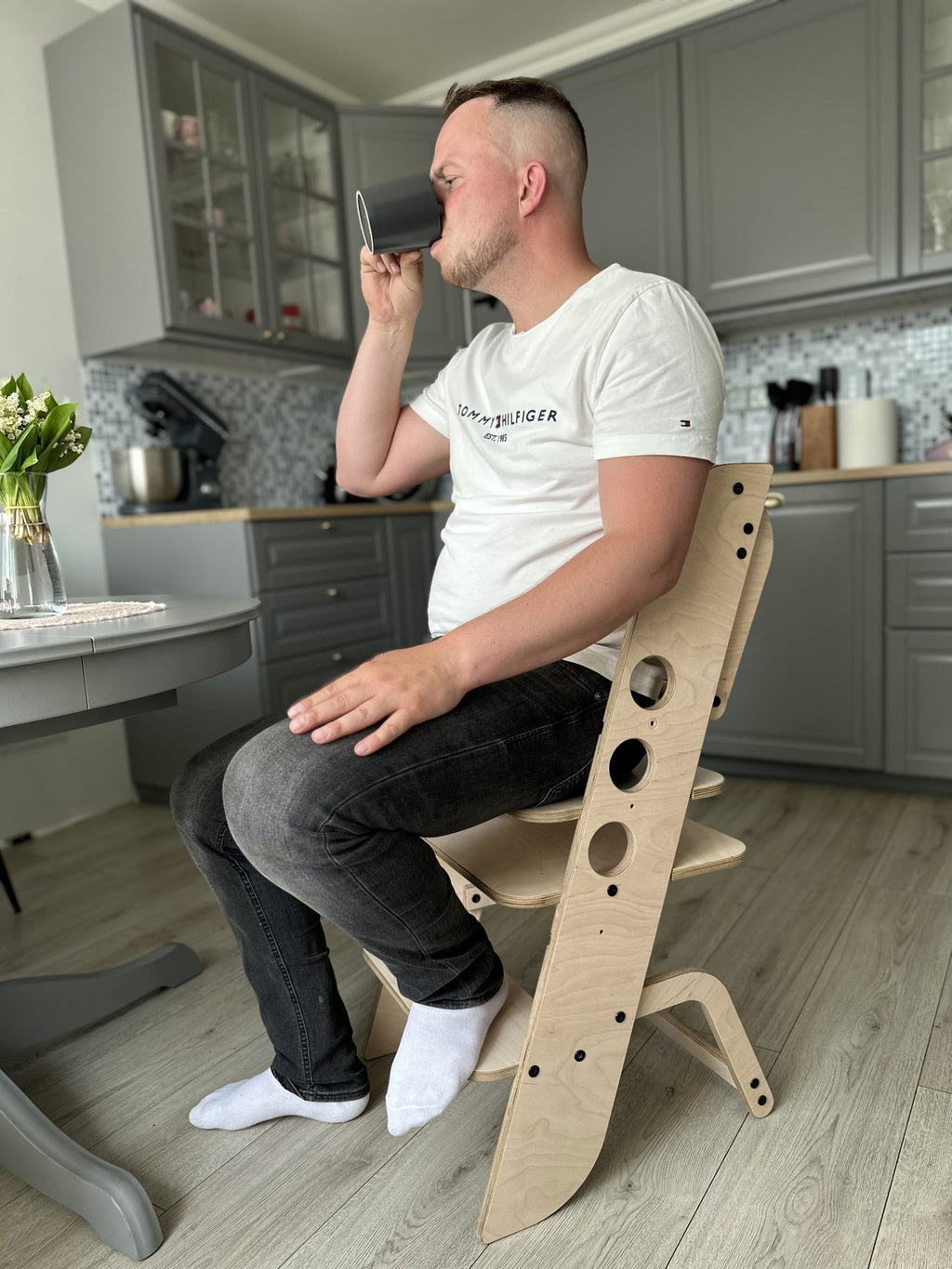 1. Adult sitting on wooden Montessori chair in a kitchen setting
