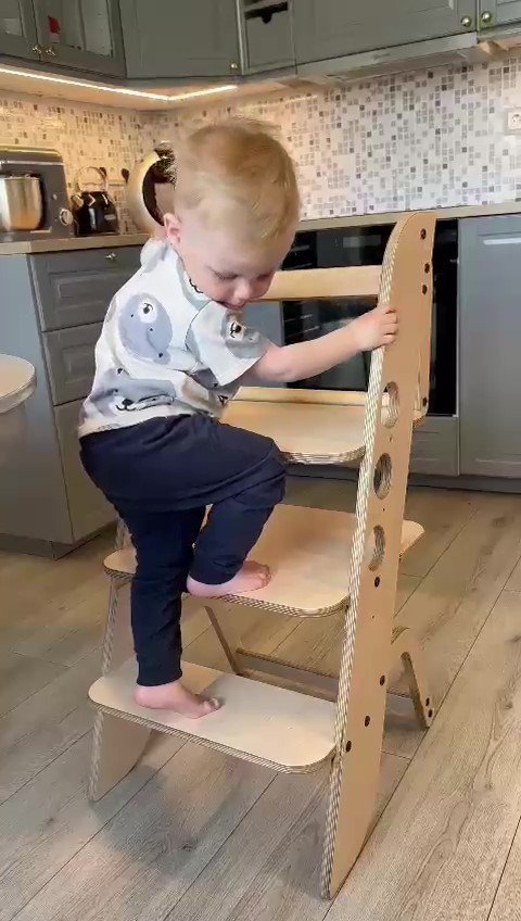1. Child climbing wooden Montessori learning tower in a kitchen