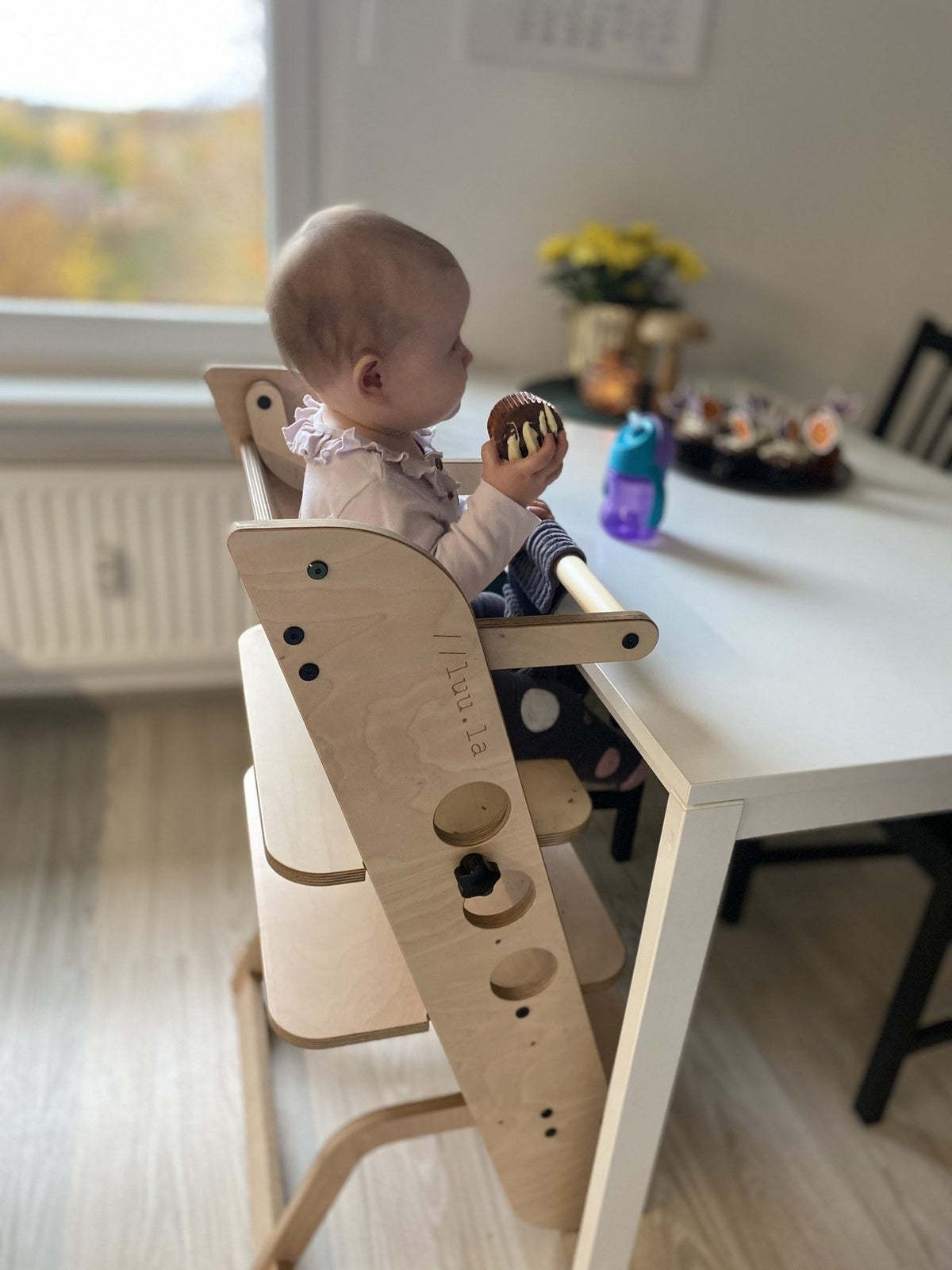 1. Baby sitting in wooden Montessori high chair at dining table