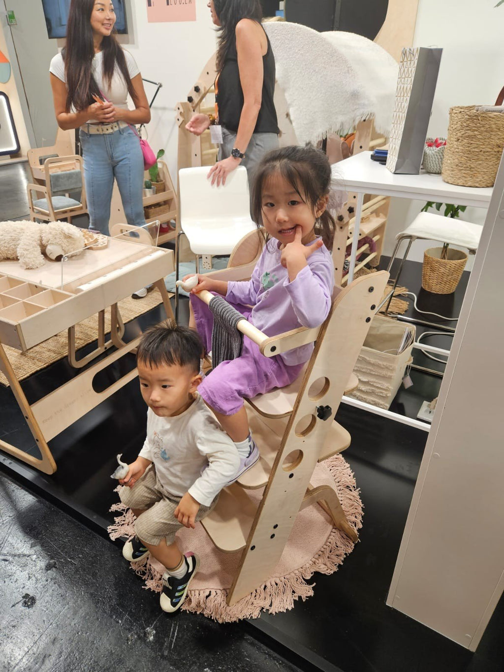 1. Two children using wooden Montessori learning tower in a playroom setting