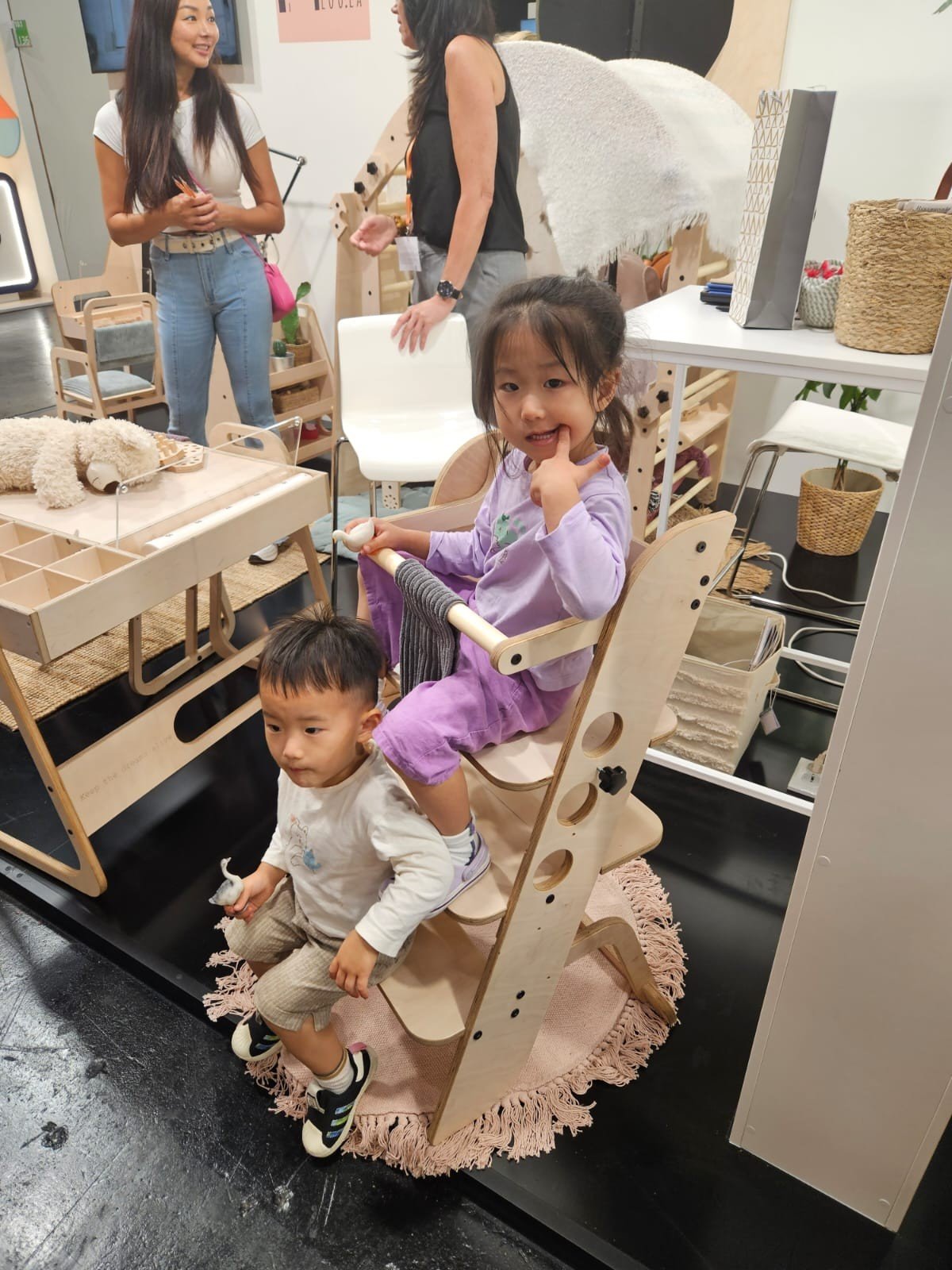 1. Two children using wooden Montessori learning tower in a playroom setting
