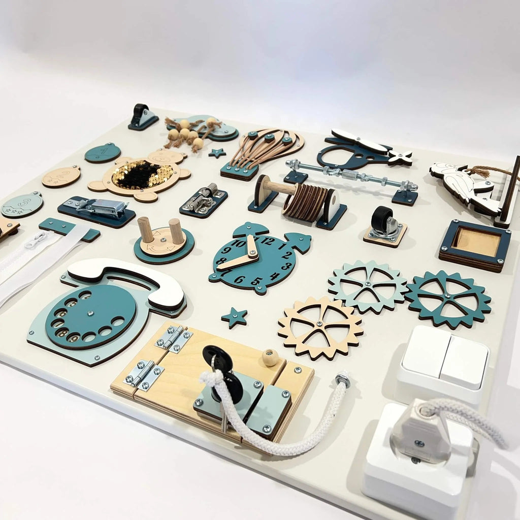 2. Montessori busy board in studio setting, highlighting teal and beige interactive elements like gears, switches, and a clock.