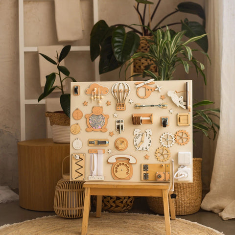1. Montessori busy board with beige and orange elements on an easel in a room with plants, designed for interactive play.