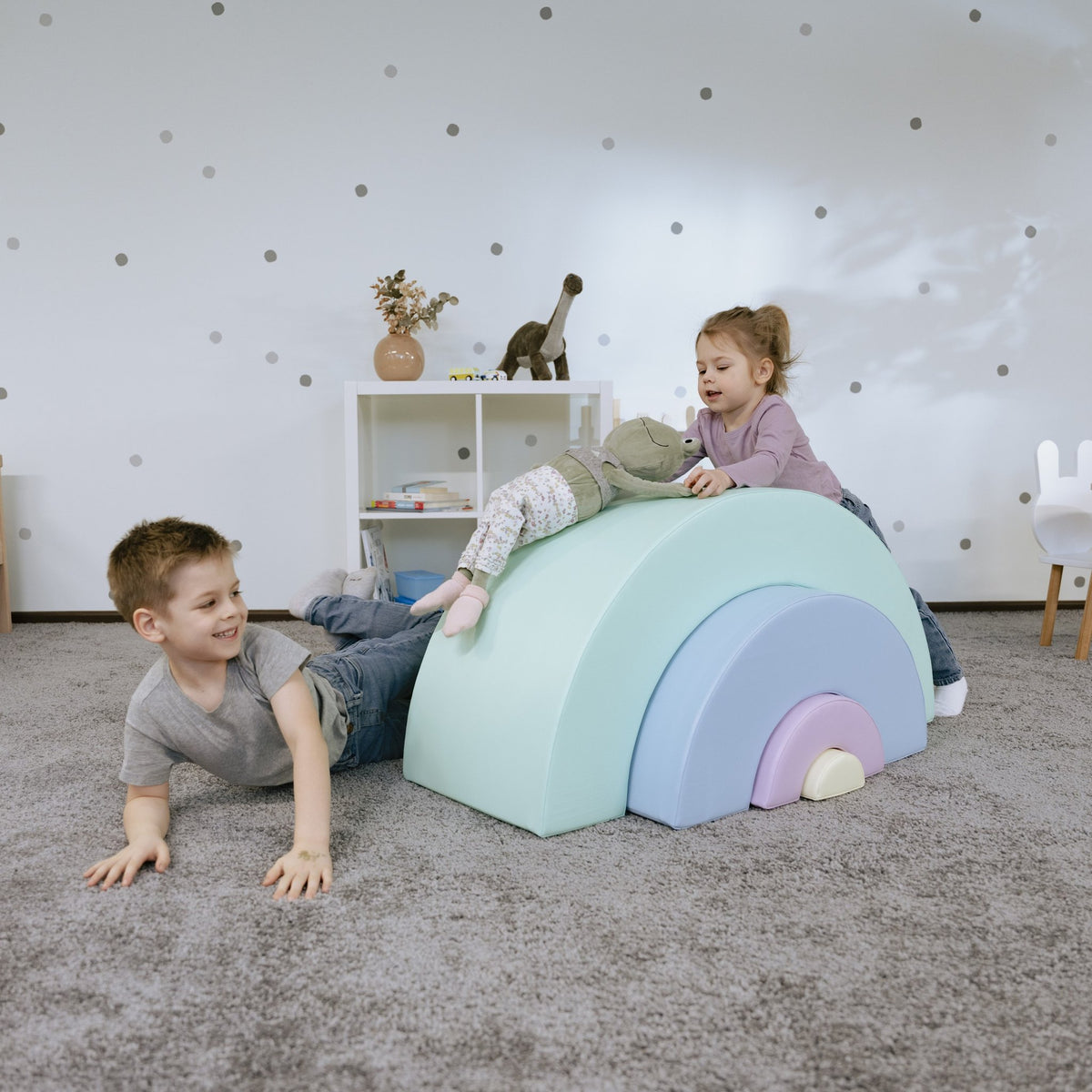 12. Boy and girl lying on pastel rainbow soft play set in playroom