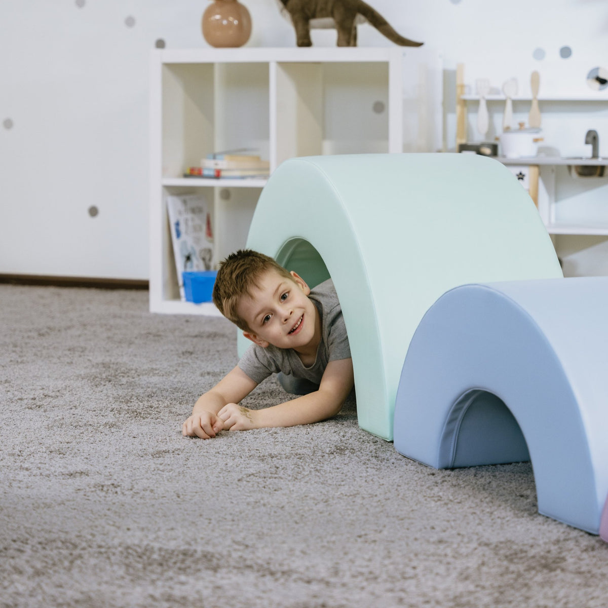 5. Boy crawling under pastel rainbow soft play set in playroom