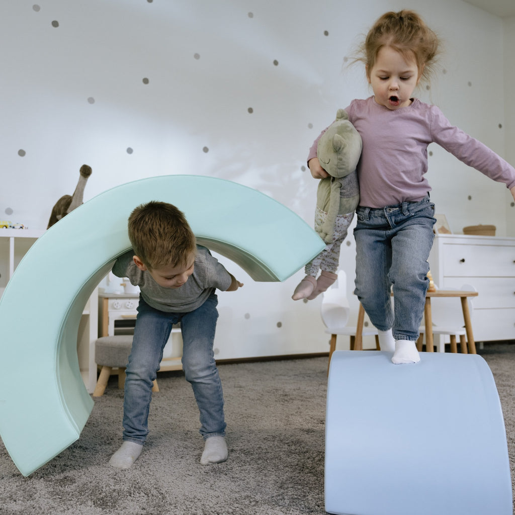 9. Boy and girl playing with pastel rainbow soft play set in playroom