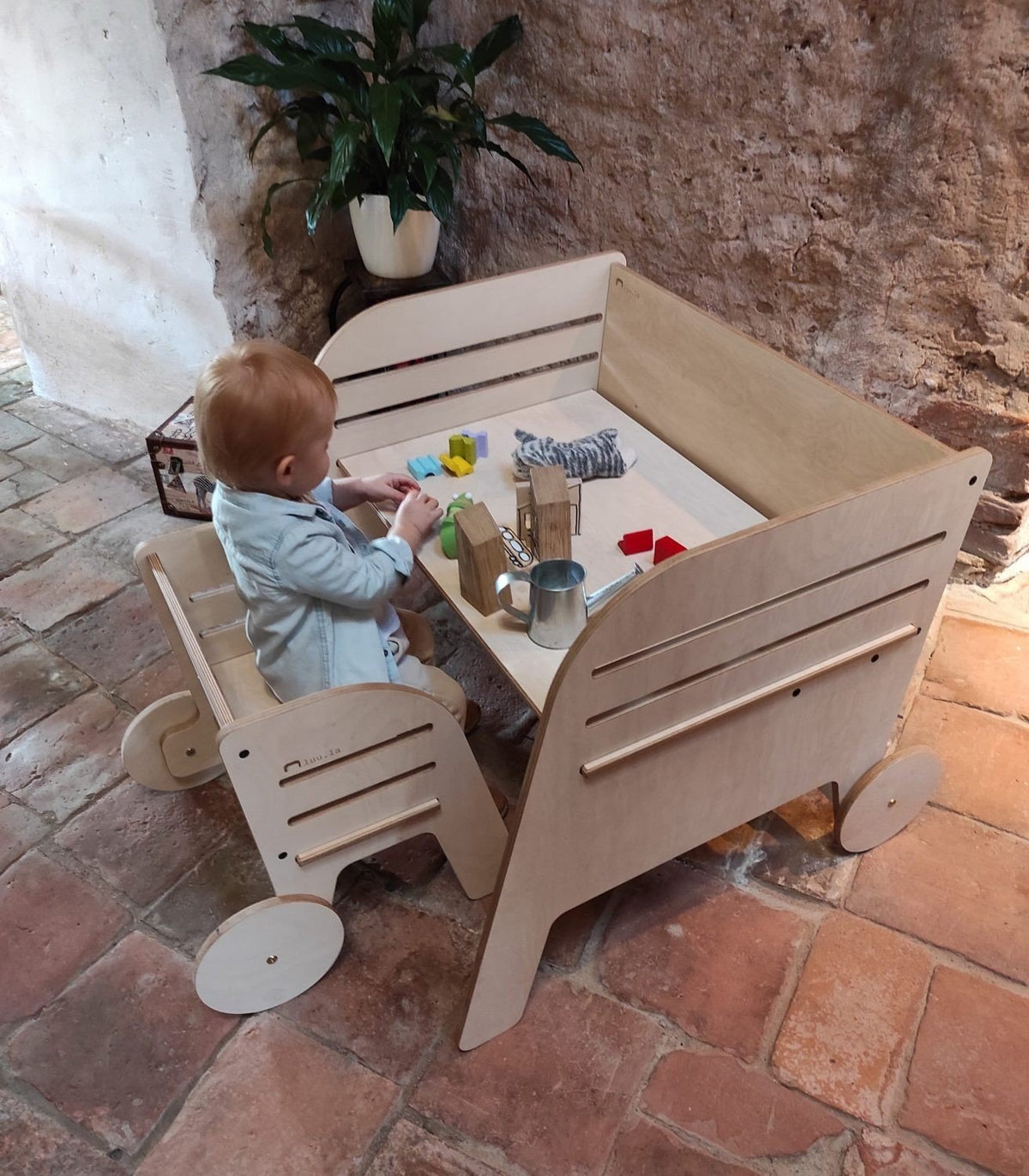 1. Child engaged with toys at Luula Montessori table and chair set, highlighting adjustable height and personal space in rustic setting