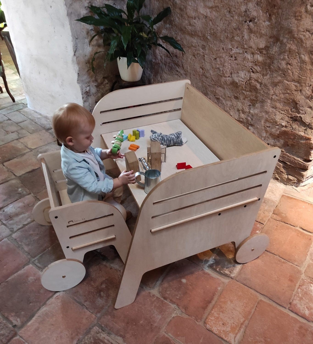 1. Child playing with toys at Luula Montessori table and chair set in rustic interior, emphasizing adjustable design and creative space
