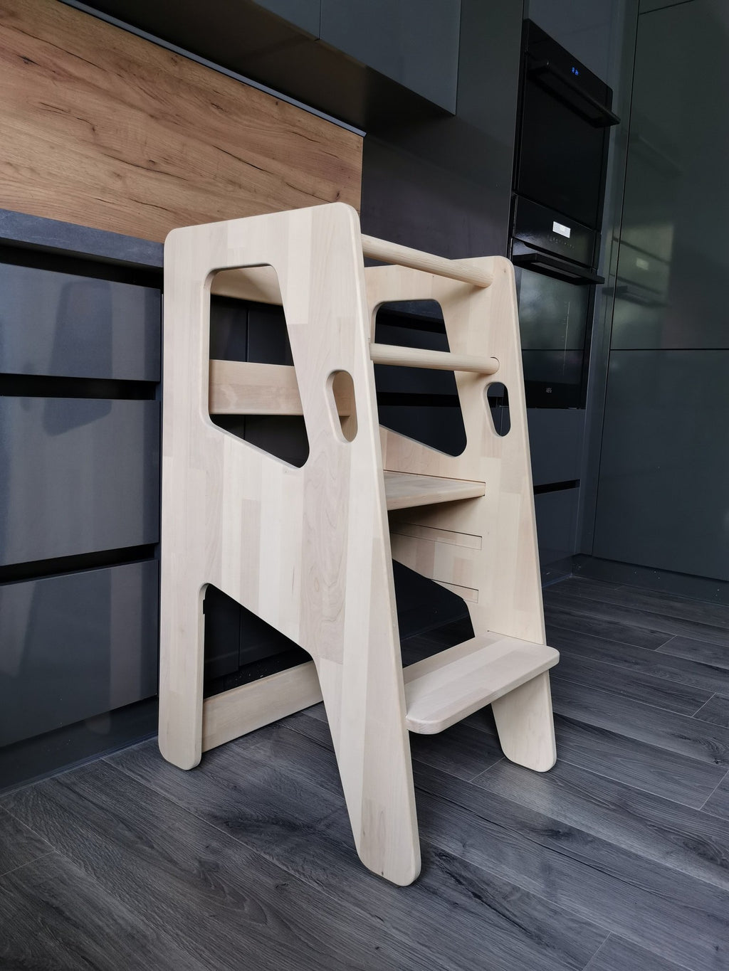 2. Natural birch wood Montessori Tower Safety+ in a modern kitchen setting, highlighting its sturdy construction and adjustable steps