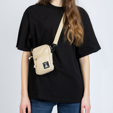 1. Woman wearing beige Moomin 80 cross body bag by NordicBuddies over black t-shirt and jeans