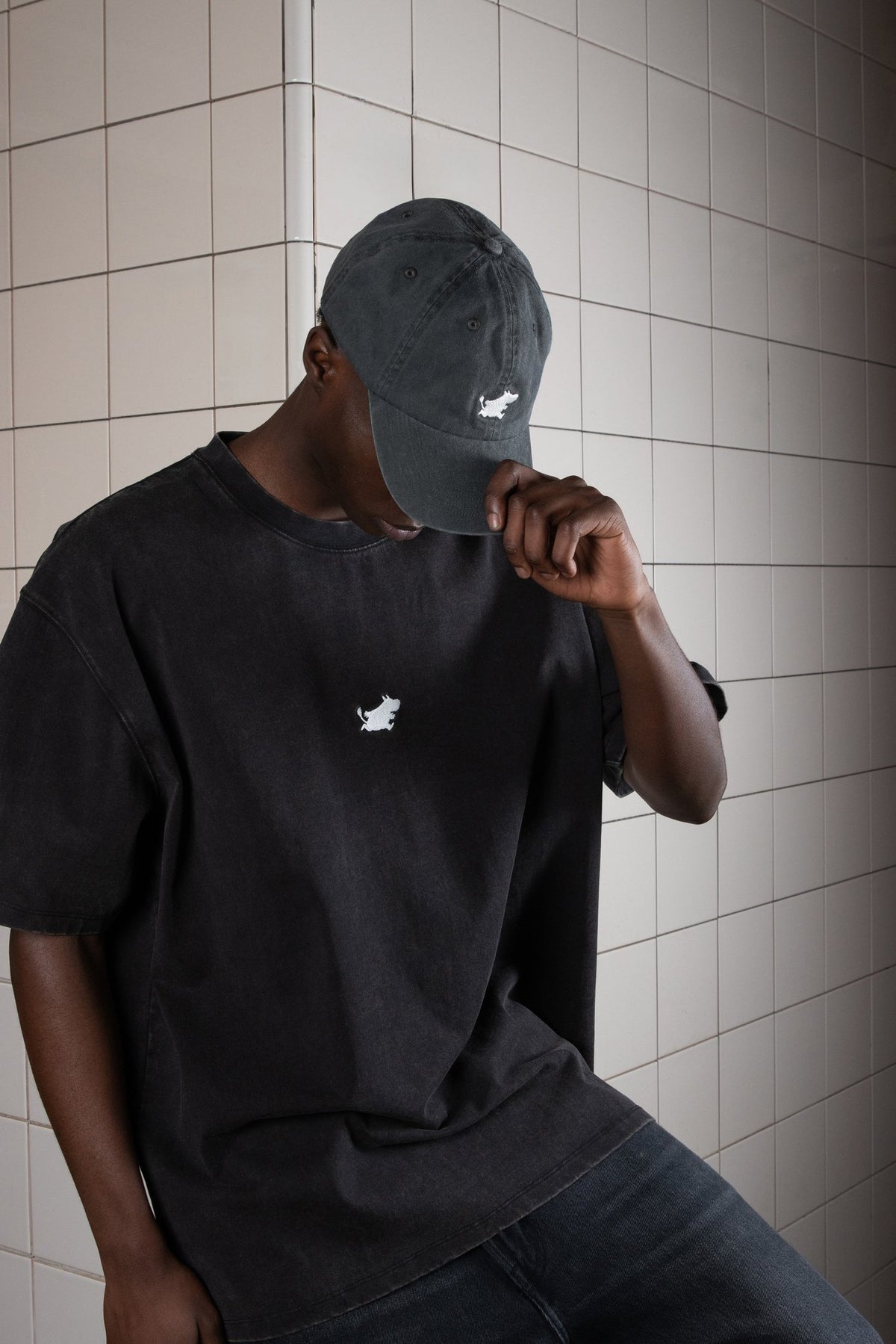 2. Man wearing Moomin Classics Denim Dad Cap in dark grey, styled with matching t-shirt in lifestyle setting