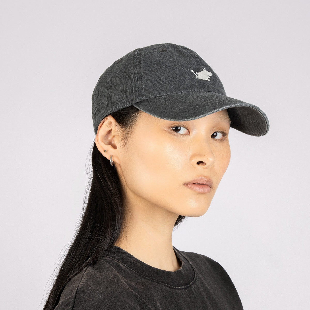 1. Woman wearing Moomin Classics Denim Dad Cap in dark grey, showcasing adjustable fit and embroidered logo